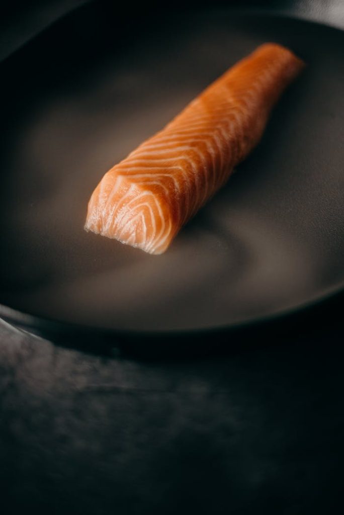 Raw salmon fillet steaming in a skillet, ideal for healthy cooking concepts.